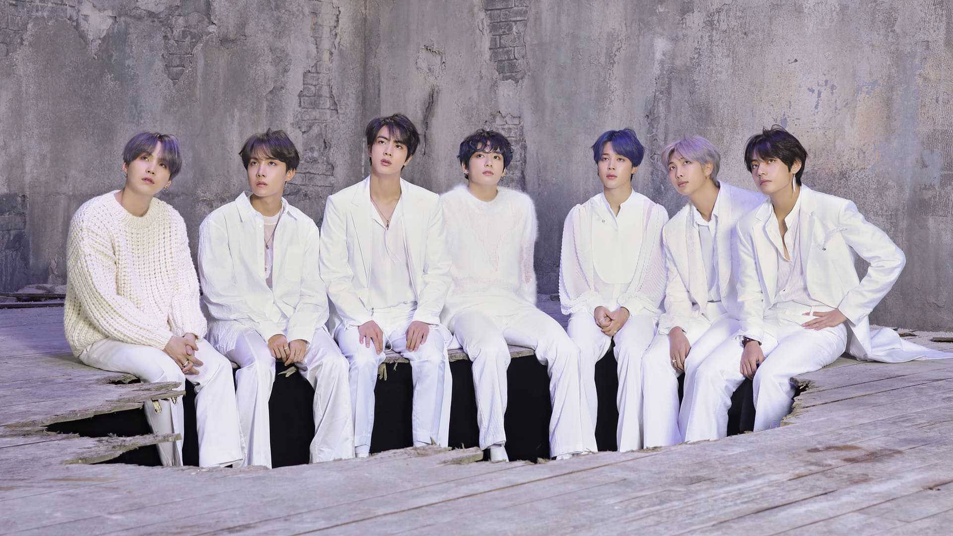 BTS 可愛風格：破洞背景白西裝 壁紙 — 七個身穿白色服裝的男人坐在木製平台上，背景是風化的混凝土牆。