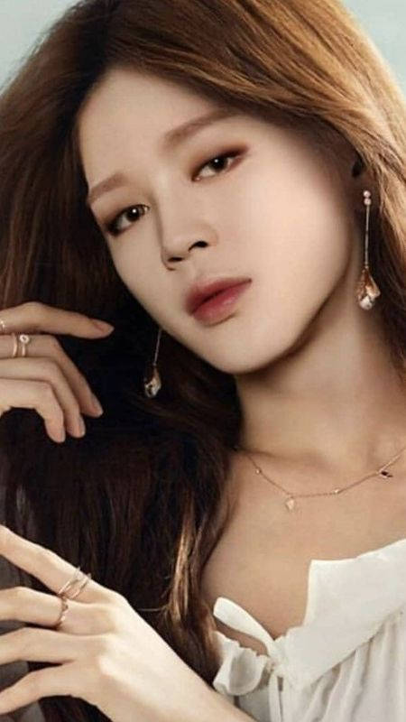 長棕色頭髮的女性穿著白色襯衫和金色珠寶的攝影棚肖像。