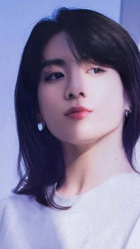 深色頭髮、戴著精緻耳環的年輕女性，在柔和藍光中。