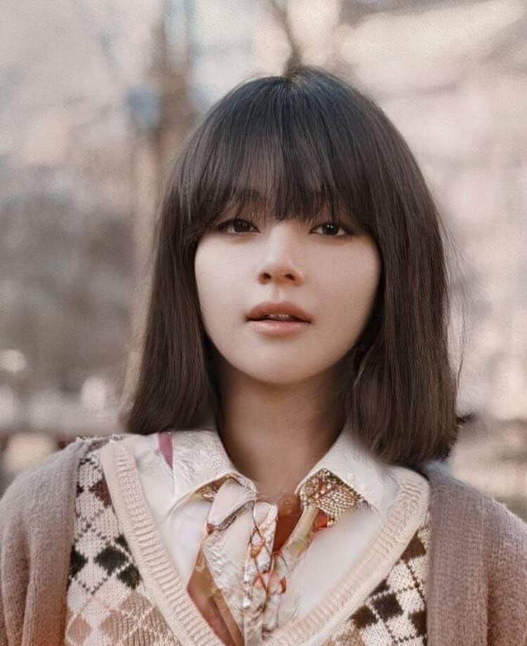 留著深色鮑伯頭的年輕女性，在戶外穿著印花毛衣背心和花卉圖案襯衫。