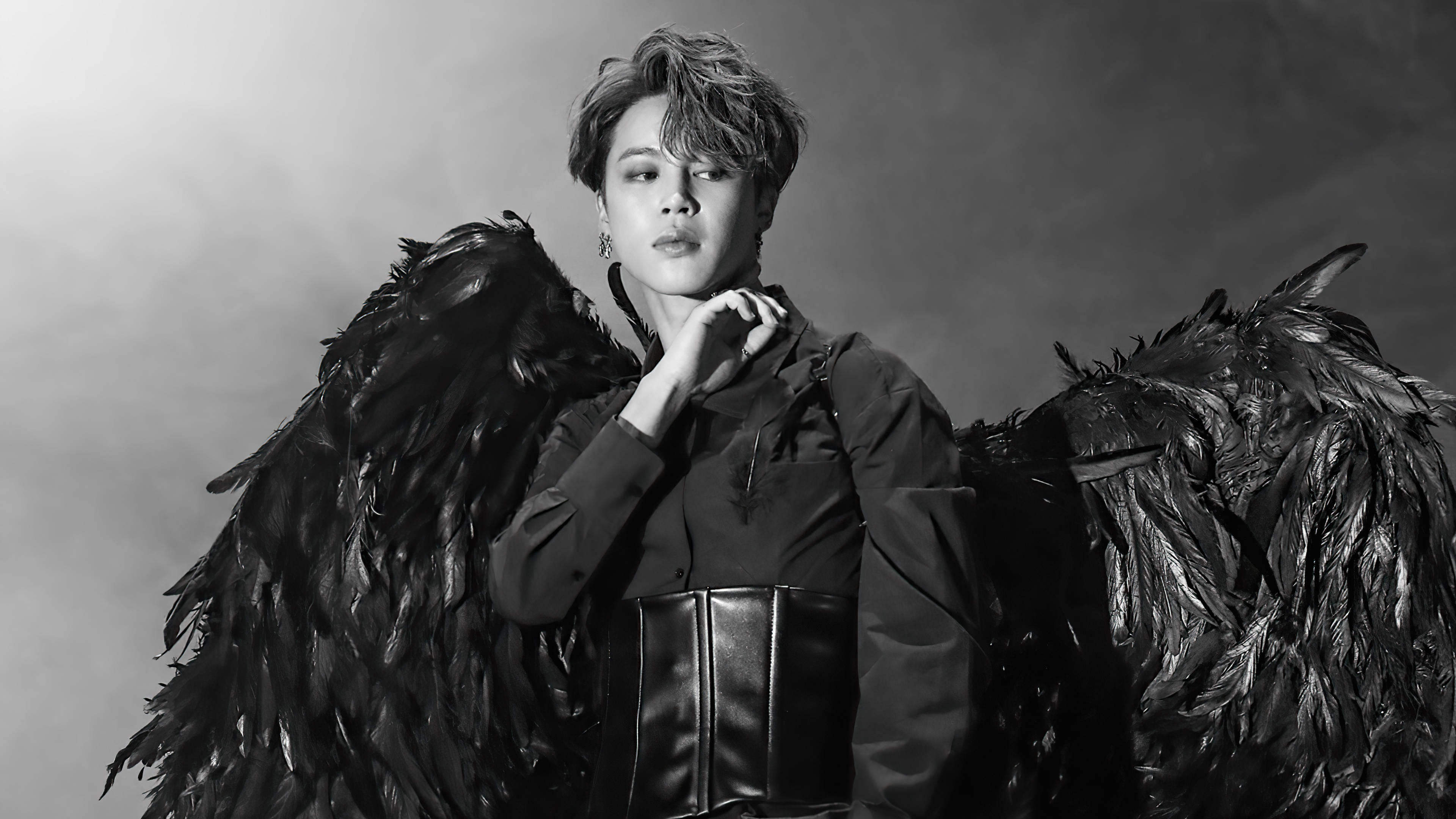 BTS 崔然竣 黑鵲 壁紙 — 一個擁有深色羽毛翅膀的人，在充滿氣氛的黑白工作室照片中戲劇性地擺姿勢。