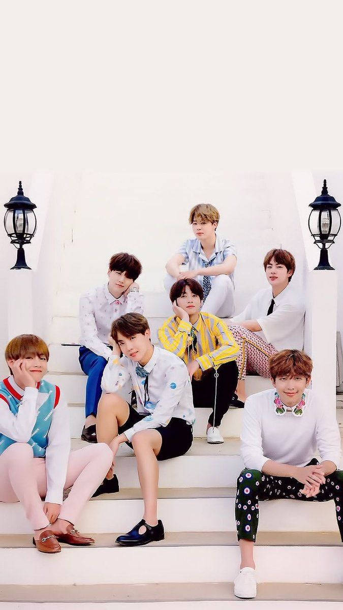 BTS - 成功的倒影 壁紙 — 七位身穿色彩繽紛服裝的年輕男性在明亮的日光下，在兩旁有黑色燈籠的白色石階上隨意擺姿勢。