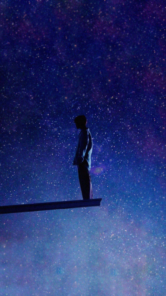 一個人在星空宇宙天空下站在木板上的剪影。