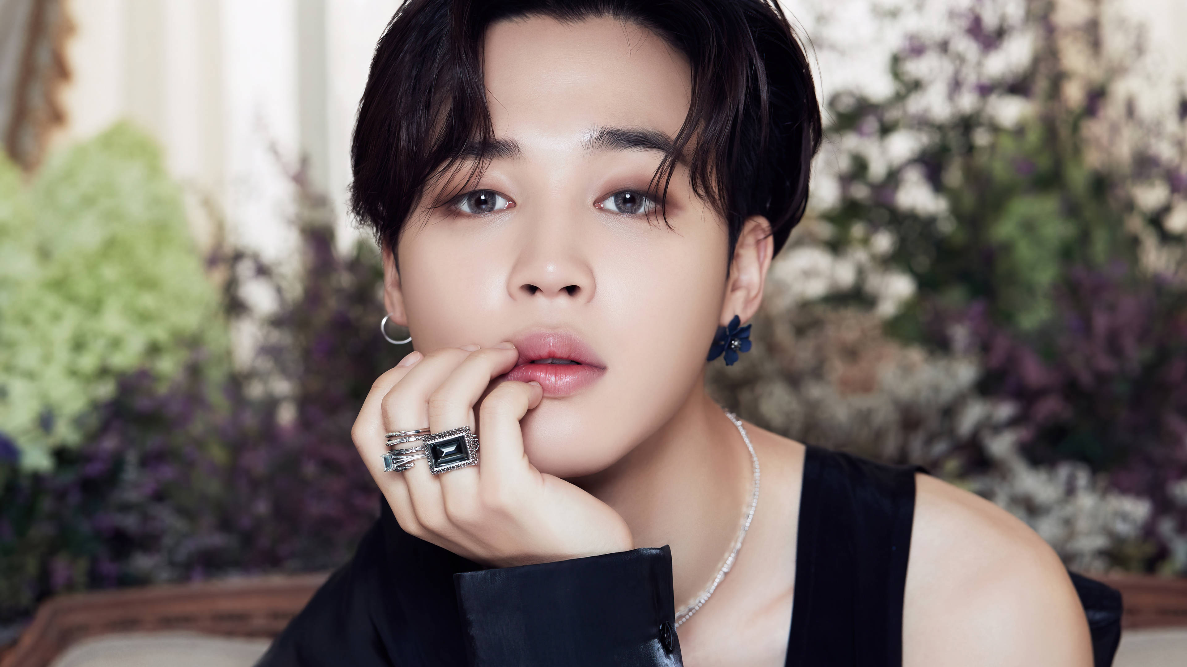 BTS 朴智旻 BE專輯 壁紙 — 一位黑髮、戴著大膽耳環的年輕男子，托腮沉思，手上戴著戒指。