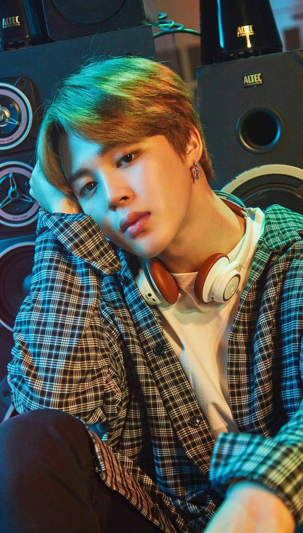 BTS 朴智旻 BTS World 壁紙 — 一位擁有彩色頭髮的年輕男子戴著耳機，穿著格仔襯衫，在霓虹燈光下靠在錄音室揚聲器上。