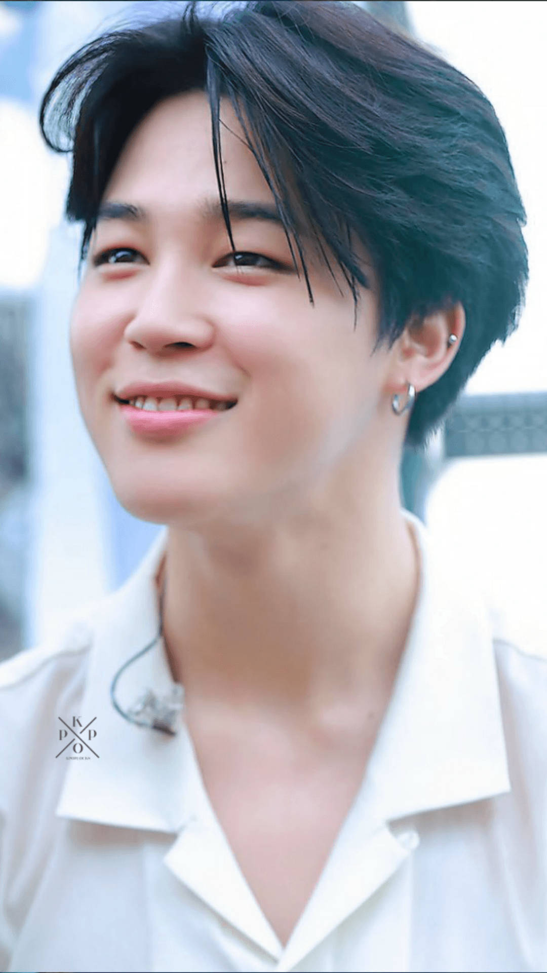 BTS 朴智旻 可愛男孩 壁紙 — 一位黑髮、笑容溫暖的年輕男子，穿著白色有領襯衫，背景明亮模糊。