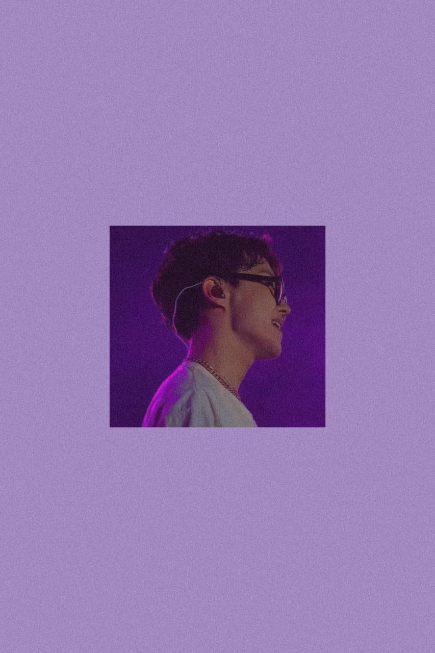 BTS 洪知秀 紫色美學 壁紙 — 一位戴眼鏡和耳機的年輕男子在充滿活力的紫色背景前溫柔微笑。