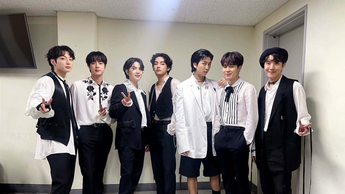 BTS 白黑配色後台照 壁紙 — 七位時尚年輕男士穿著黑白搭配的服裝，在普通的室內走廊自信地擺姿勢。