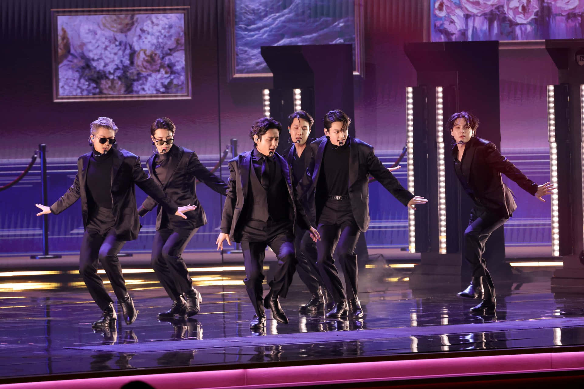 BTS 第64屆格萊美頒獎典禮表演照片 壁紙 — 五名身穿黑色西裝的男子在紫色和藍色燈光下的光澤舞台上表演同步舞蹈動作。