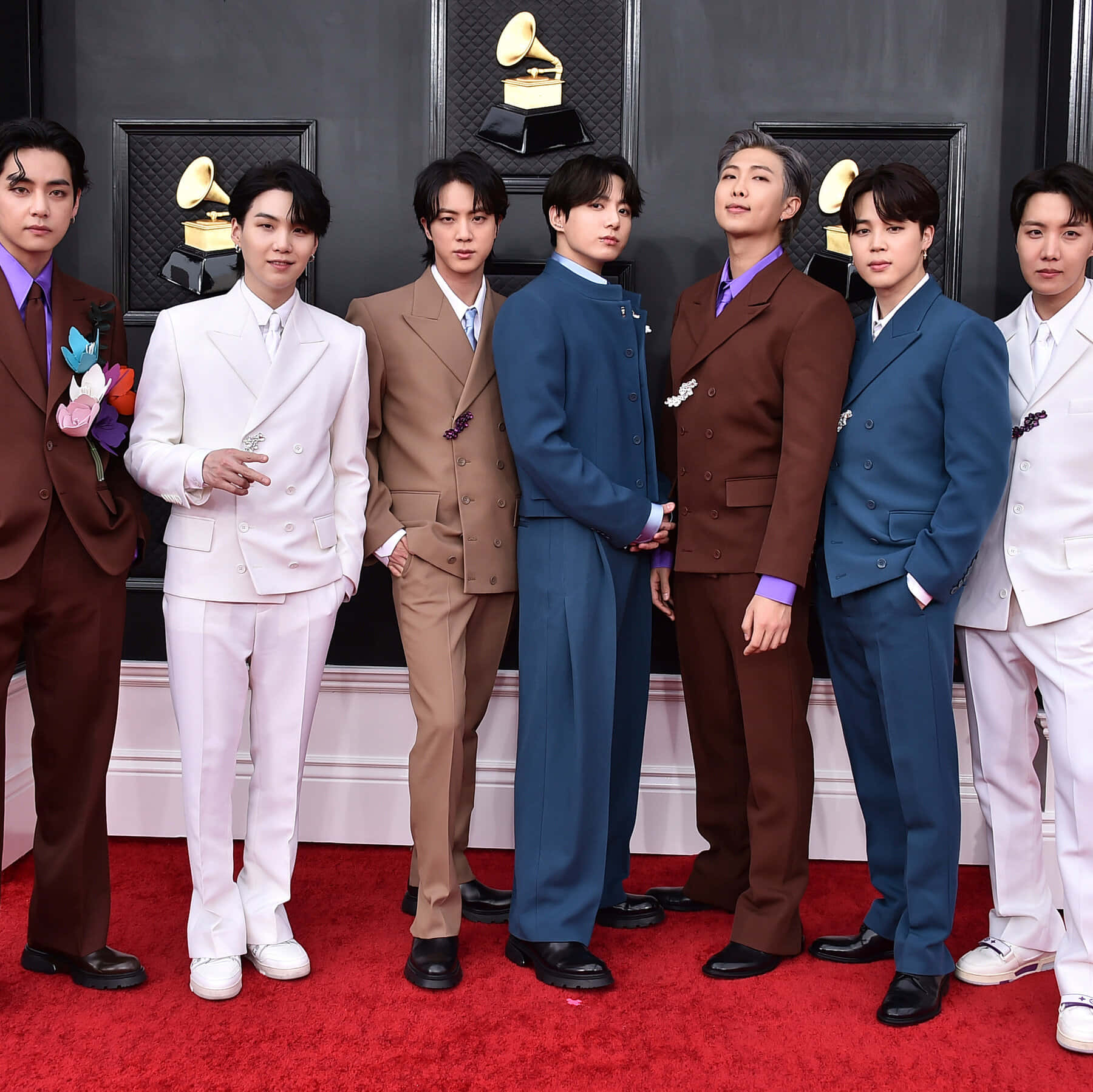 BTS 紅毯禮服照 壁紙 — 七位身穿時尚西裝的男士在葛萊美獎背景下自信地在紅地毯上擺姿勢。