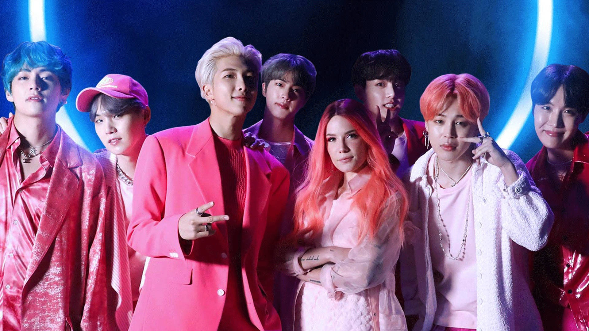 K-pop團體在藍色舞台燈光下穿著色彩繽紛的服裝擺姿勢。
