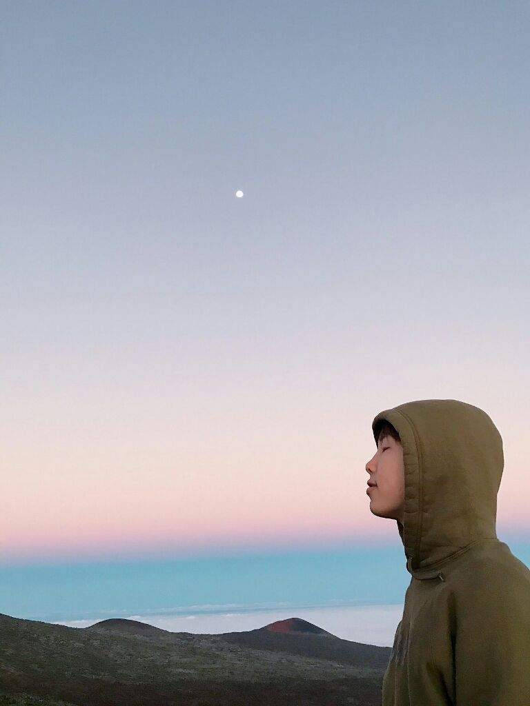 BTS 金南俊 Sky 壁紙 — 一個穿著連帽衫的人凝視著暮色中平靜海洋上升起的月亮。