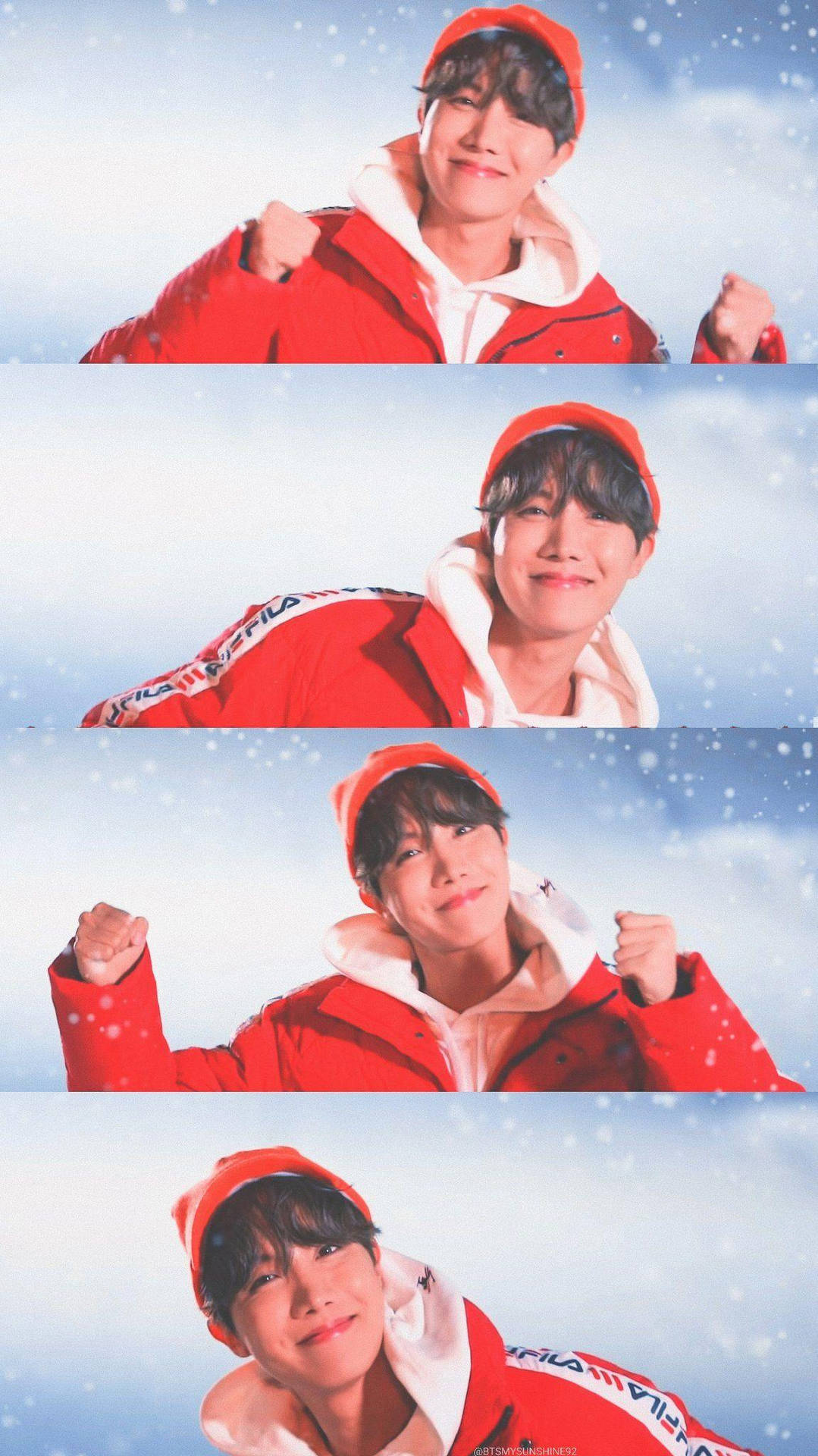 BTS 金昇玟 冬季 2020 壁紙 — 一個穿著紅色冬季夾克和帽子的年輕男子，在雪景天空背景下自信地舉起拳頭擺姿勢。