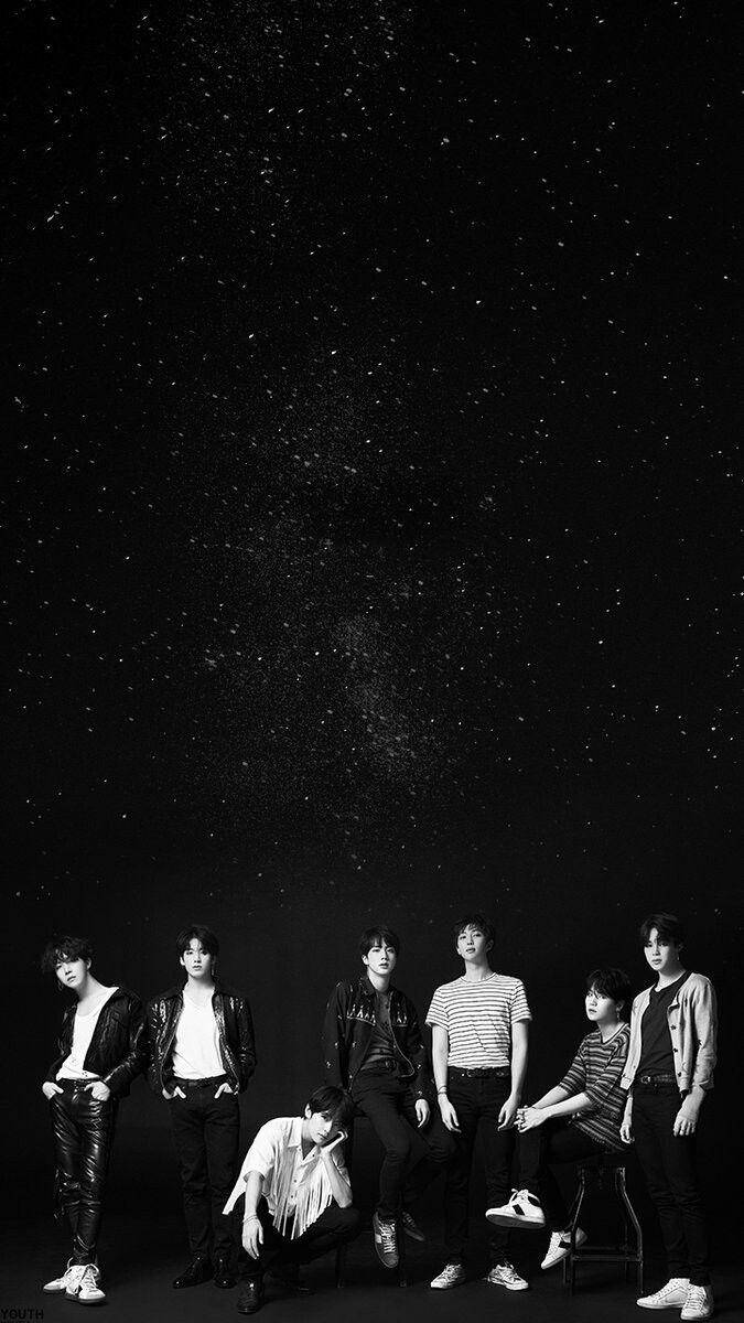 七位穿著休閒服的年輕男性在星空下擺姿勢。
