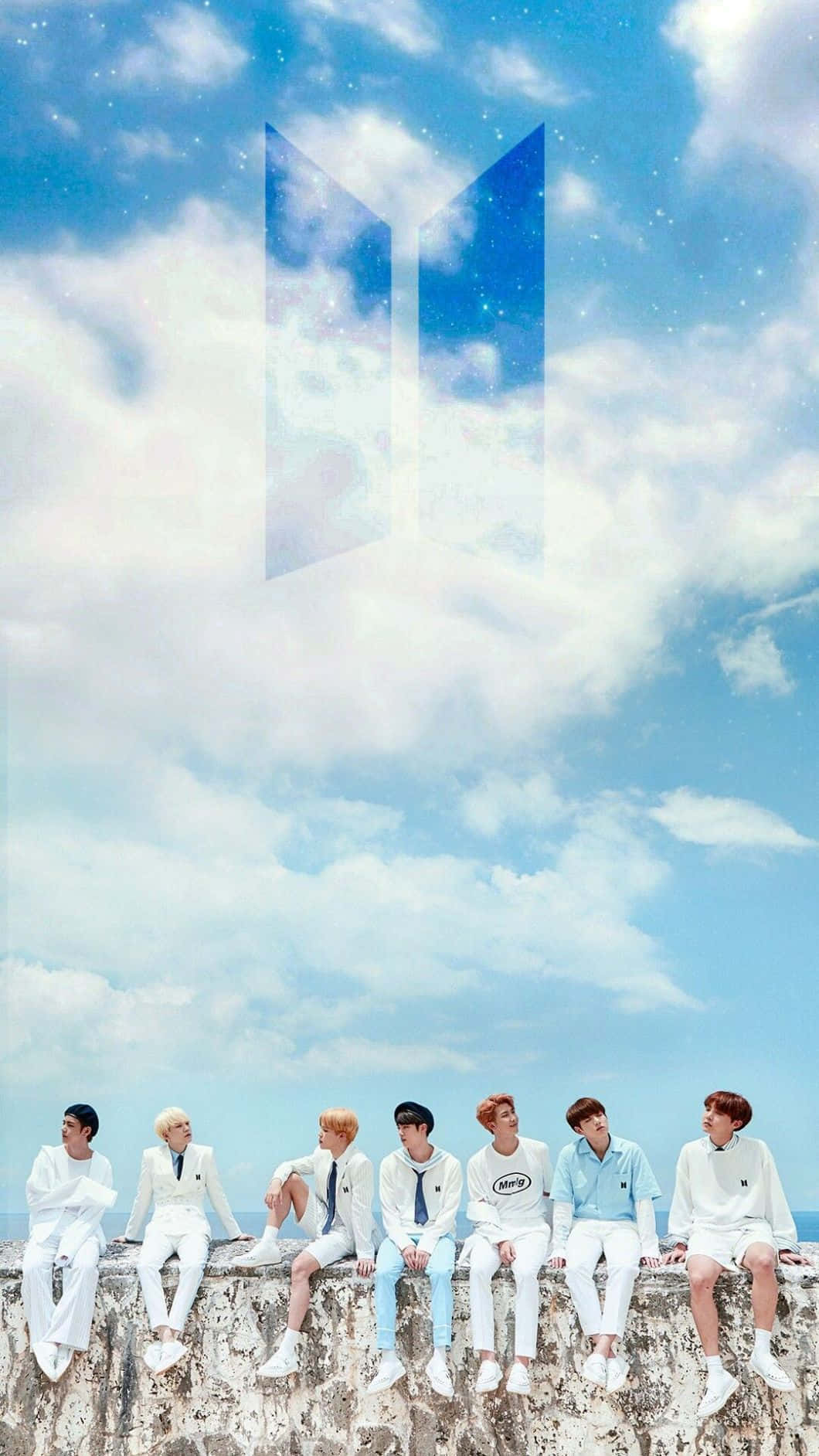 BTS夢幻iPhone壁紙 壁紙 — 七個身穿白色服裝的男人坐在石頭邊緣上，天空湛藍，有蓬鬆的雲朵，上方漂浮著發光的BTS標誌。