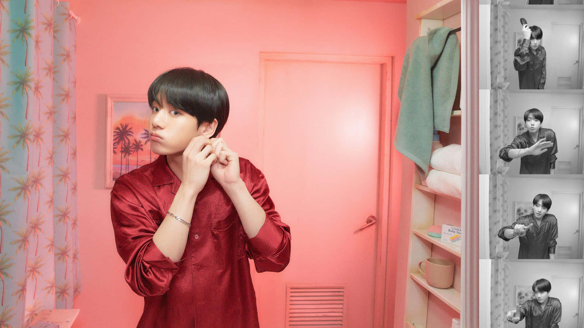 BTS成員Jungkook悠閒公園休憩 壁紙 — 一位身穿紅色緞面襯衫的年輕男子在一個帶有圖案窗簾和衣櫃的粉紅色房間裡調整他的耳機。