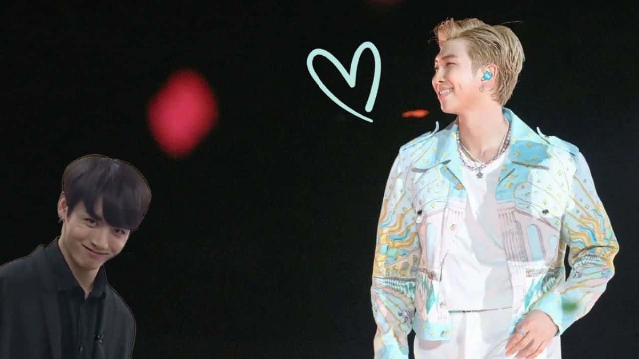 BTS成員RM舞台表演 壁紙 — 兩位微笑的男性表演者在舞台上，一位穿黑色襯衫，另一位穿彩色外套，背後有發光的心形圖案。
