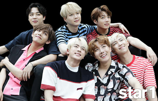 BTS成員於Star1雜誌集體照 壁紙 — 七位身穿彩色條紋襯衫的年輕男性在黑色背景前緊密地擺姿勢，帶著自信的笑容。