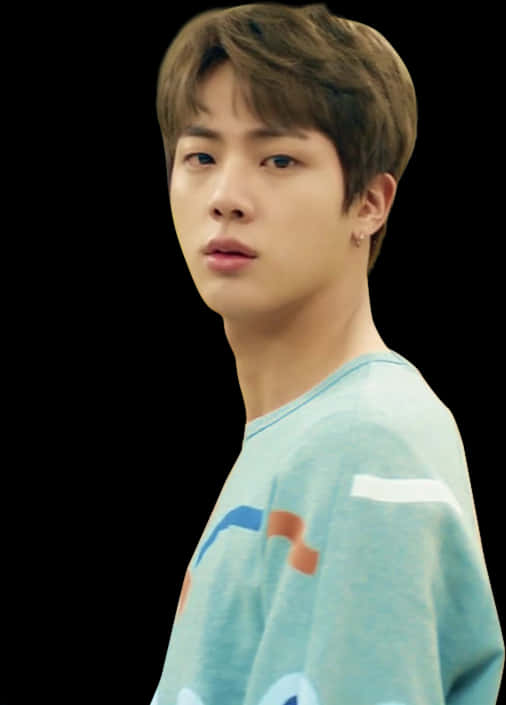 BTS成員穿藍色襯衫 壁紙 — 一位短棕髮、身穿淺藍色圖案T恤的年輕男子，在黑色背景前微微轉頭。