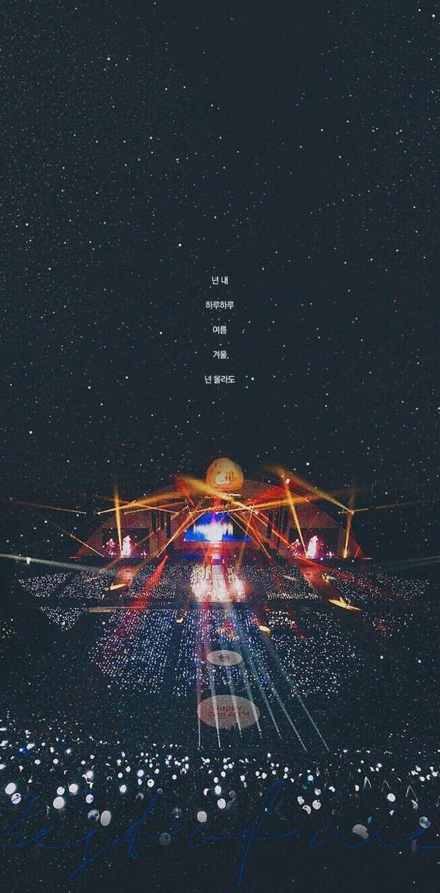 一個燈火通明的音樂會舞台，在繁星點點的夜空下，觀眾燈光閃爍。