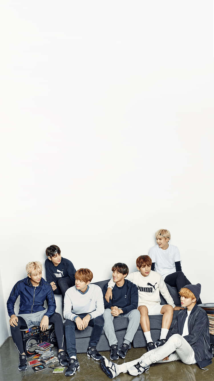BTS為PUMA拍攝宣傳照 壁紙 — 七個年輕男子穿著休閒運動服，靠著白色牆壁，懶散地坐在灰色沙發上，周圍散落著唱片和一部手提音響。