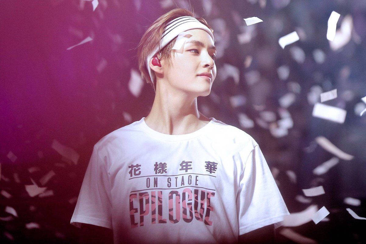 BTS田柾國白色紙屑 壁紙 — 一位身穿印有中文文字和「epilogue」的白色T恤的年輕男子，站在帶有紫色光芒的飄落彩紙下。