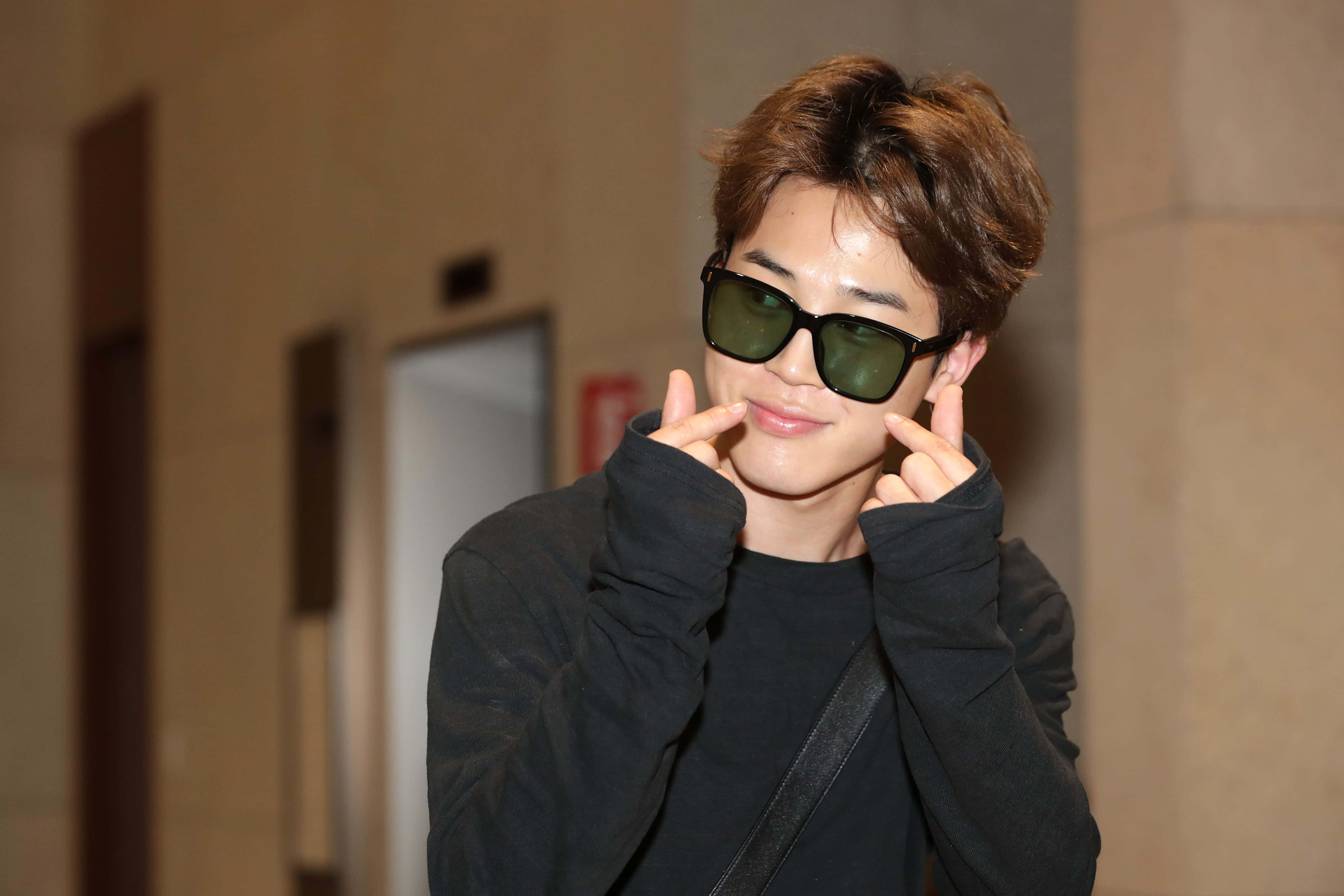 BTS的Jimin舞台光芒四射 壁紙 — 一位棕色頭髮的年輕男子戴著深色太陽眼鏡，在室內擺姿勢時做出頑皮的表情。
