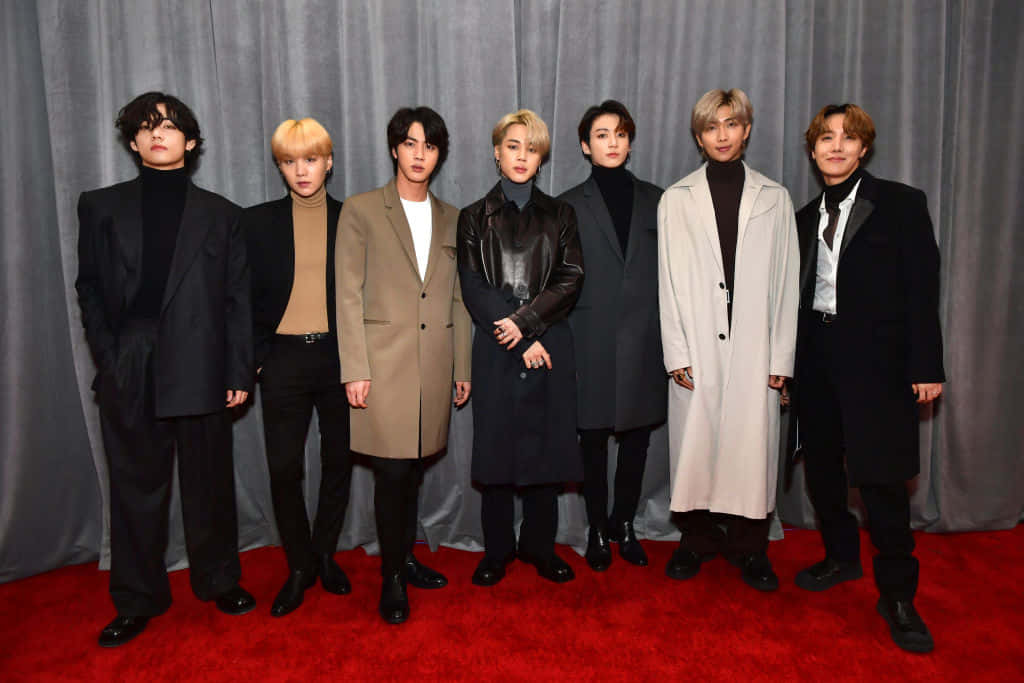 BTS第62屆格萊美紅毯照 壁紙 — 七位時尚男士身著正裝，自信地站在灰色窗簾背景前的紅地毯上。