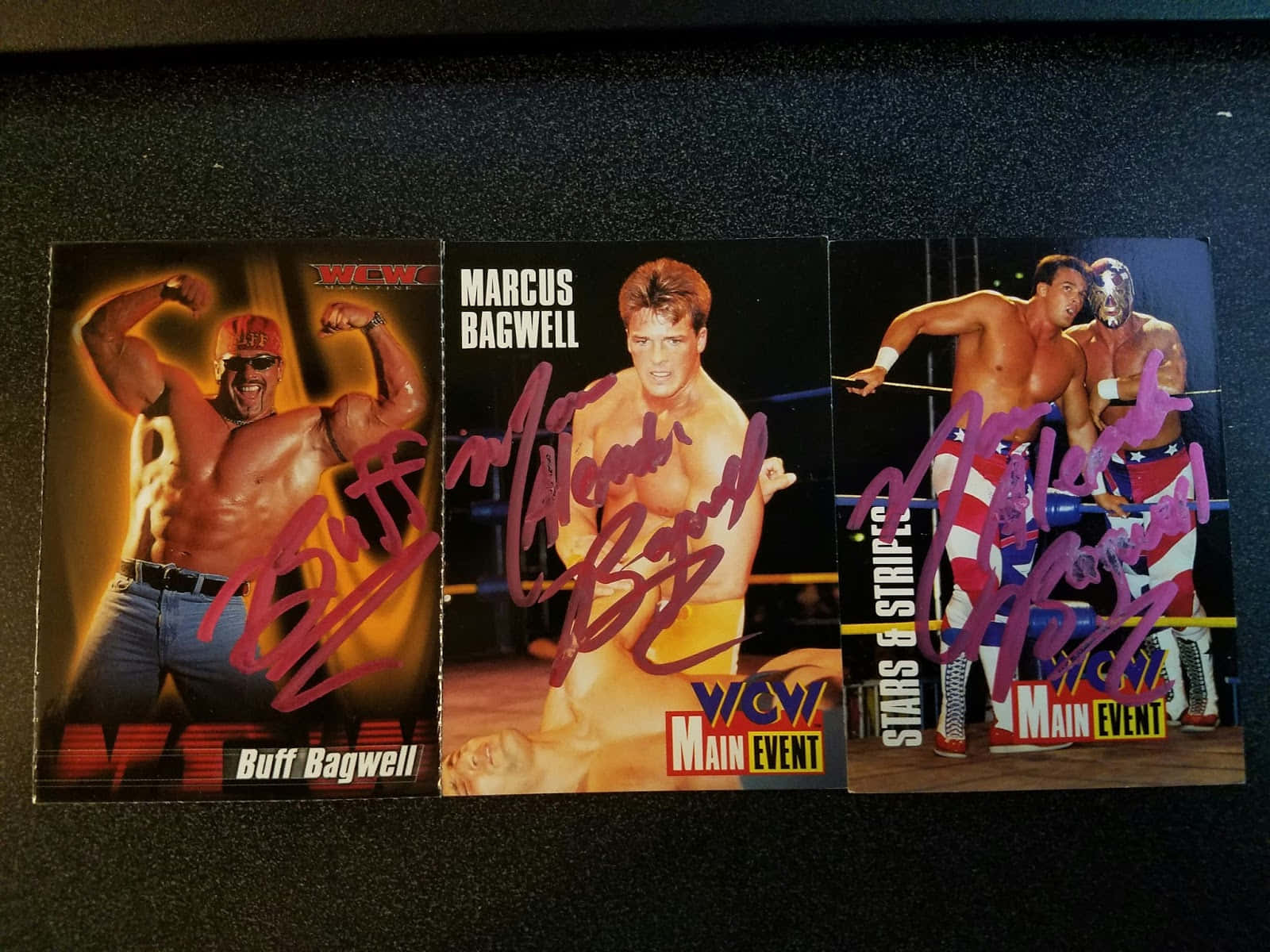 Buff Bagwell WCW 雜誌封面照片 壁紙 — 三張簽名WCW摔角交易卡， featuring Buff Bagwell、Marcus Bagwell 和一名蒙面摔角手，置於深色表面上。