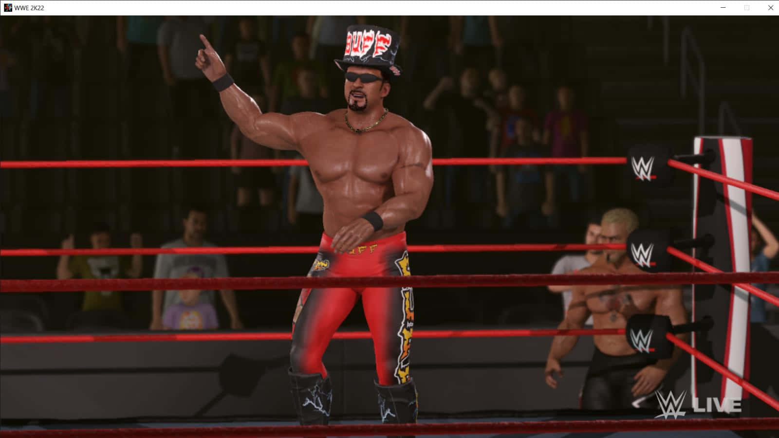 Buff Bagwell WWE 2K22 摔角遊戲 壁紙 — 一位肌肉發達的摔角手穿著紅色短褲和高帽，在WWE擂台上勝利地做手勢，背景是人群。