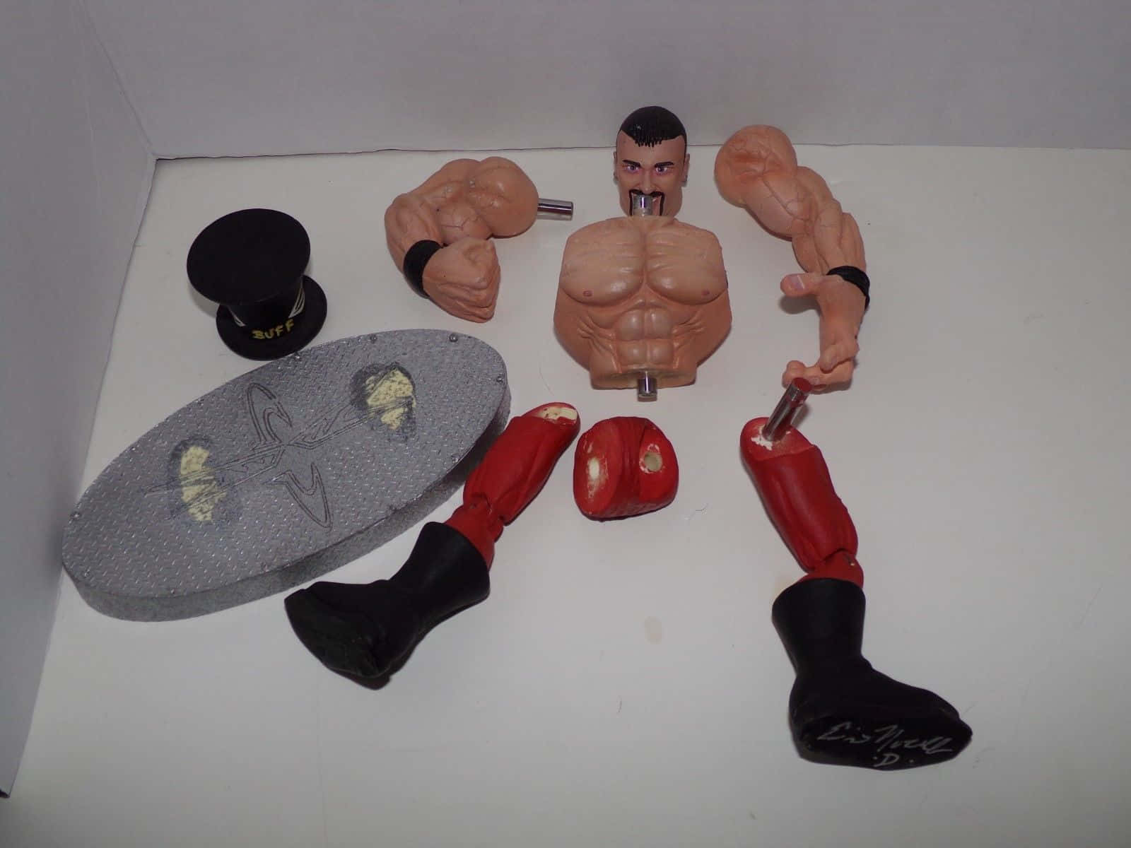 Buff Bagwell 拳擊手解構動作玩偶照片 壁紙 — 已拆解的復古動作人偶，帶有肌肉發達的軀幹、手臂、腿部及配件，擺放在白色表面上。