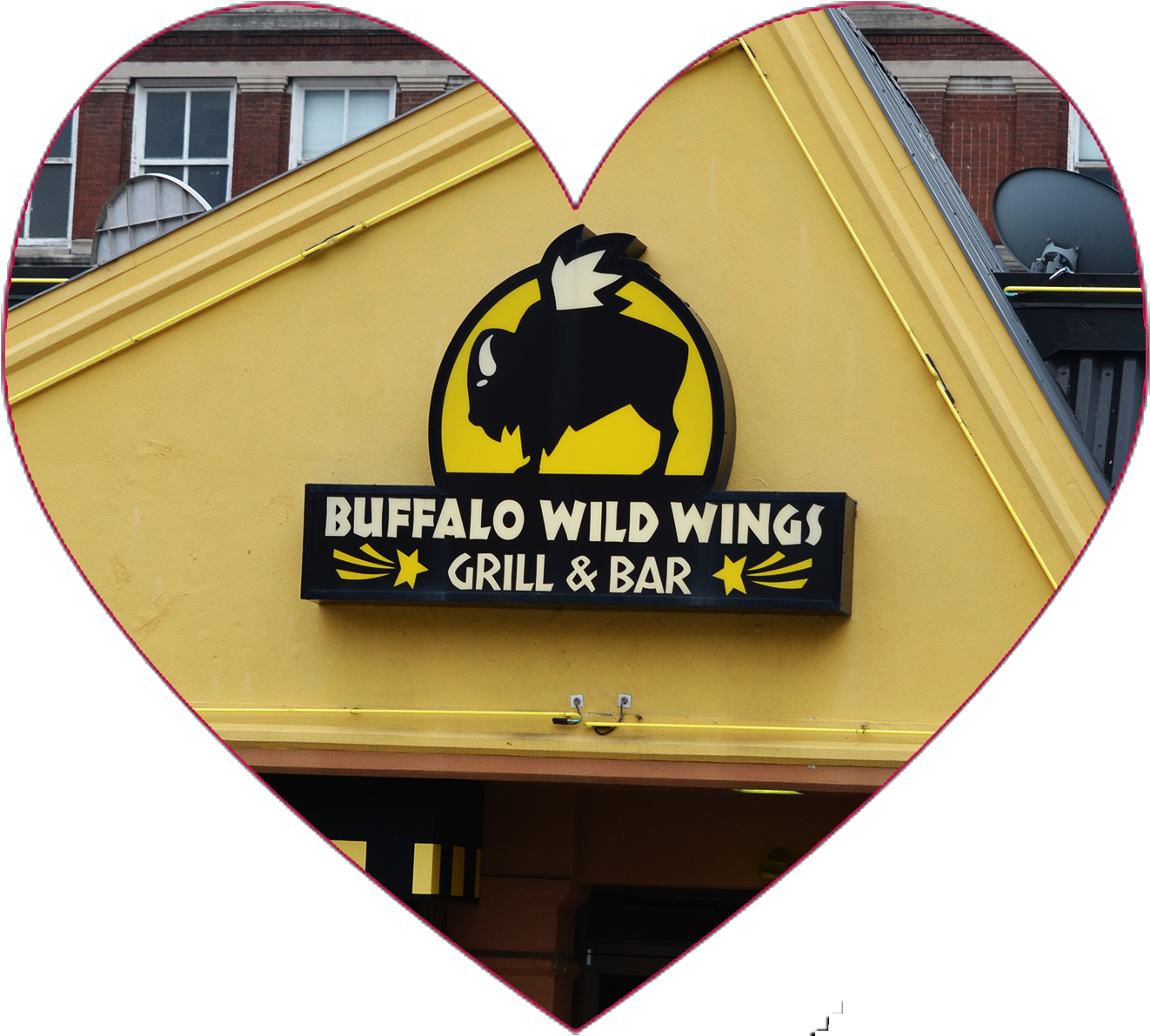 Buffalo Wild Wings 燒烤酒吧招牌 壁紙 — 心形框架突顯了 Buffalo Wild Wings 餐廳招牌，黃色背景上有黑色野牛標誌，襯托著磚砌建築外牆。