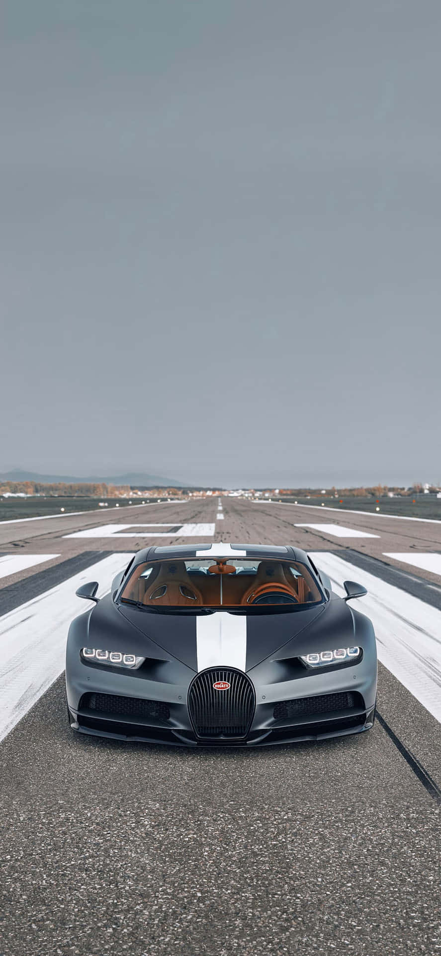 灰色Bugatti超跑帶白色條紋停在空曠跑道。