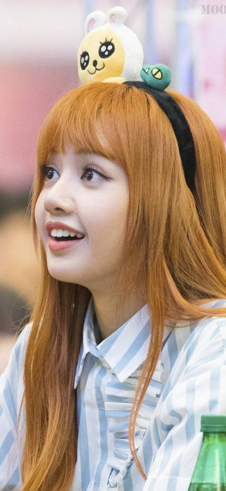 Bundang AK Plaza粉絲簽名會Lisa BLACKPINK 高畫質照片 壁紙 — 一位開朗的年輕女性，橙色頭髮，在活動中戴著可愛的毛絨兔頭帶微笑。