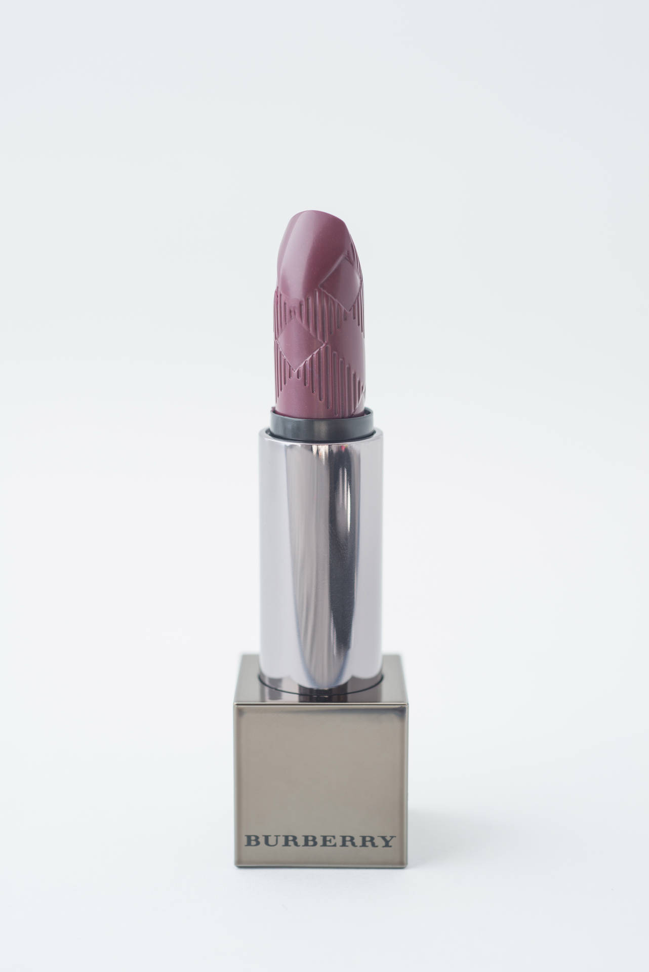 Burberry紫紅色唇膏放在品牌底座上，白色背景