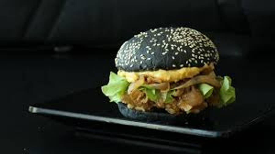 令人垂涎的 Burger King Whopper 壁紙 — 一款黑芝麻籽美食漢堡，搭配脆皮煙肉、生菜和醬汁，優雅地擺放在深色背景下的時尚黑色餐盤上。