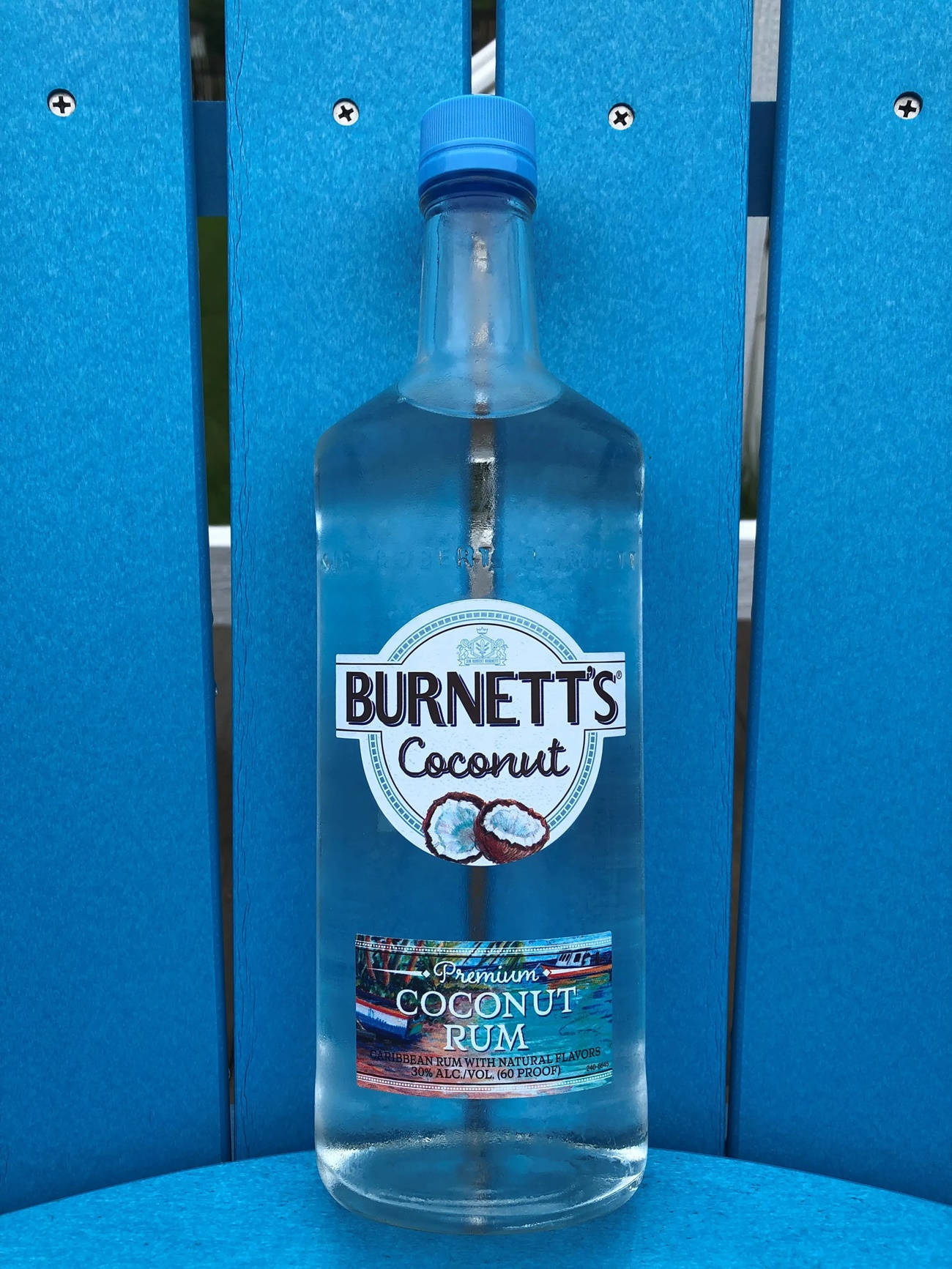 一瓶Burnett's Coconut Rum放在藍色木椅上。