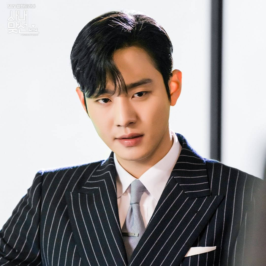 《Business Proposal》恐龍造型康泰茂 壁紙 — 一位穿著筆挺條紋西裝的男士，在簡約的攝影棚背景下，神情嚴肅地凝視著。