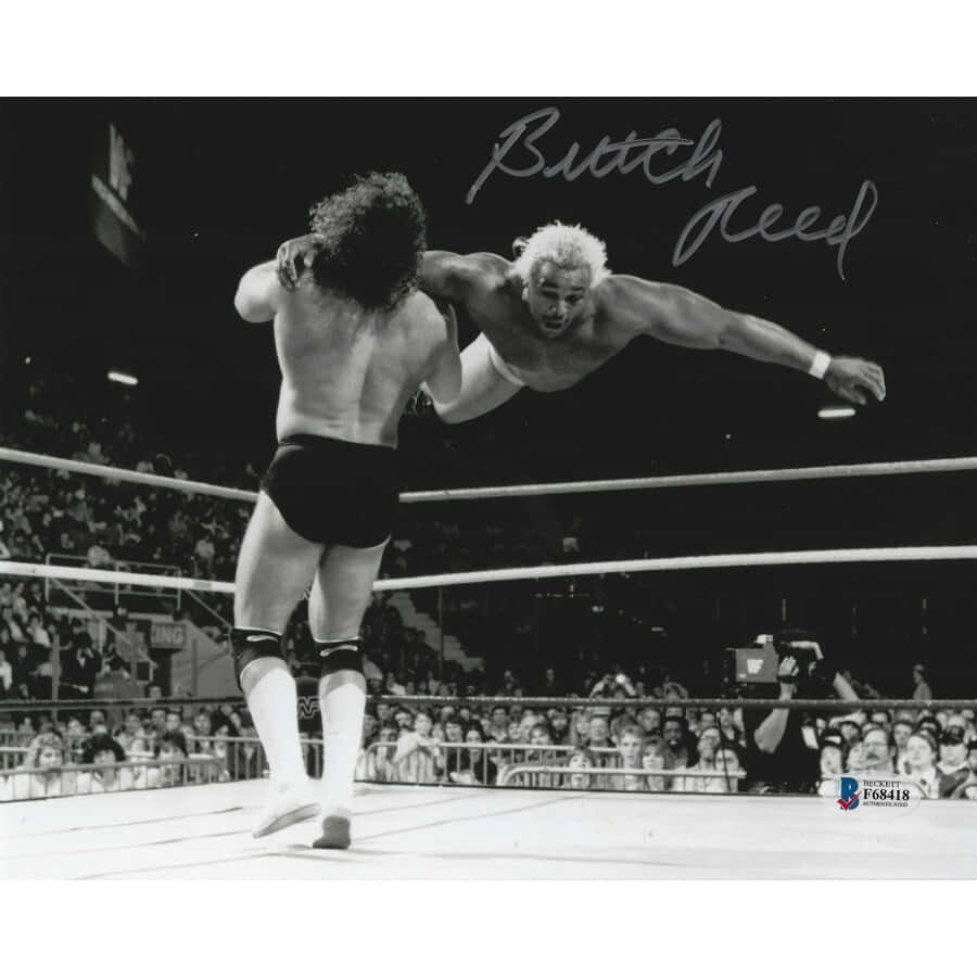 Butch Reed 獨特戰鬥風格 壁紙 — 一張黑白照片捕捉到摔角手 Butch Reed 在半空中對對手執行飛行動作，身處擁擠的摔角擂台內。