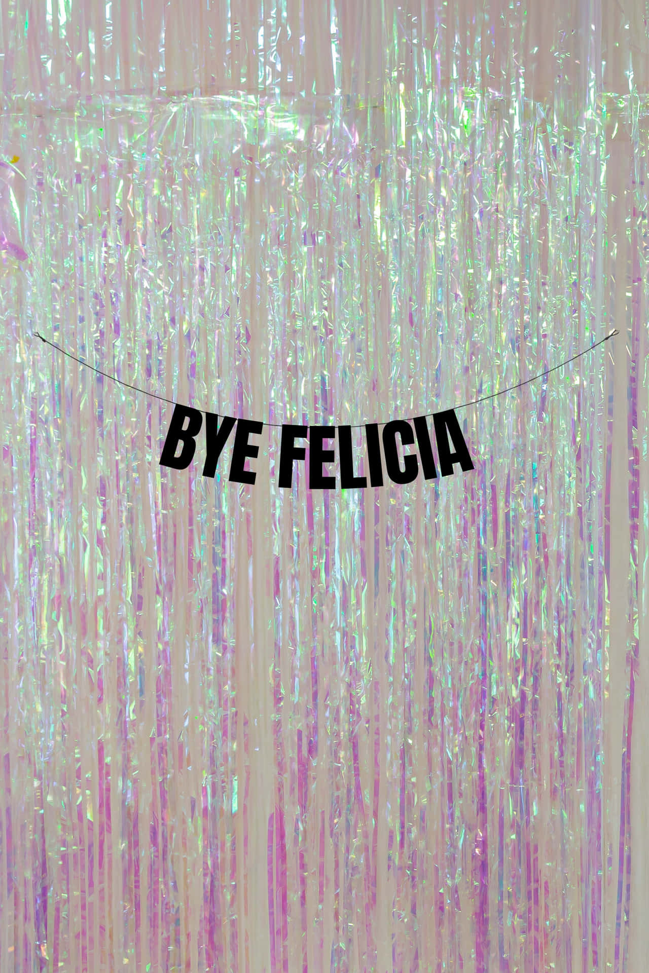  壁紙 — 一個寫有 'BYE FELICIA' 的節日橫幅掛在閃爍虹彩粉紅和紫色調的金屬絲帶上。