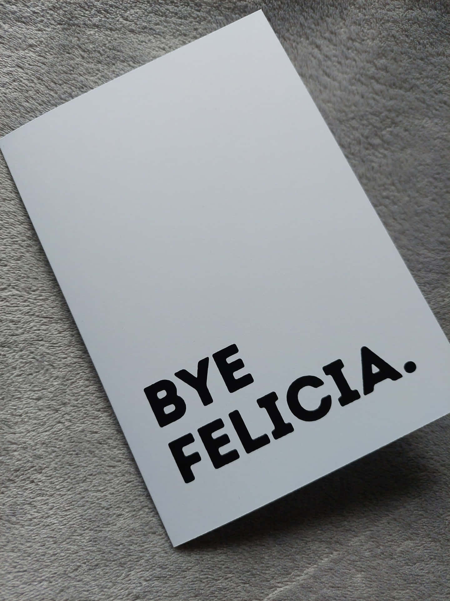  壁紙 — 一張白色卡片，上面有粗體黑色文字寫著「BYE FELICIA.」，放在有紋理的灰色布料表面上。