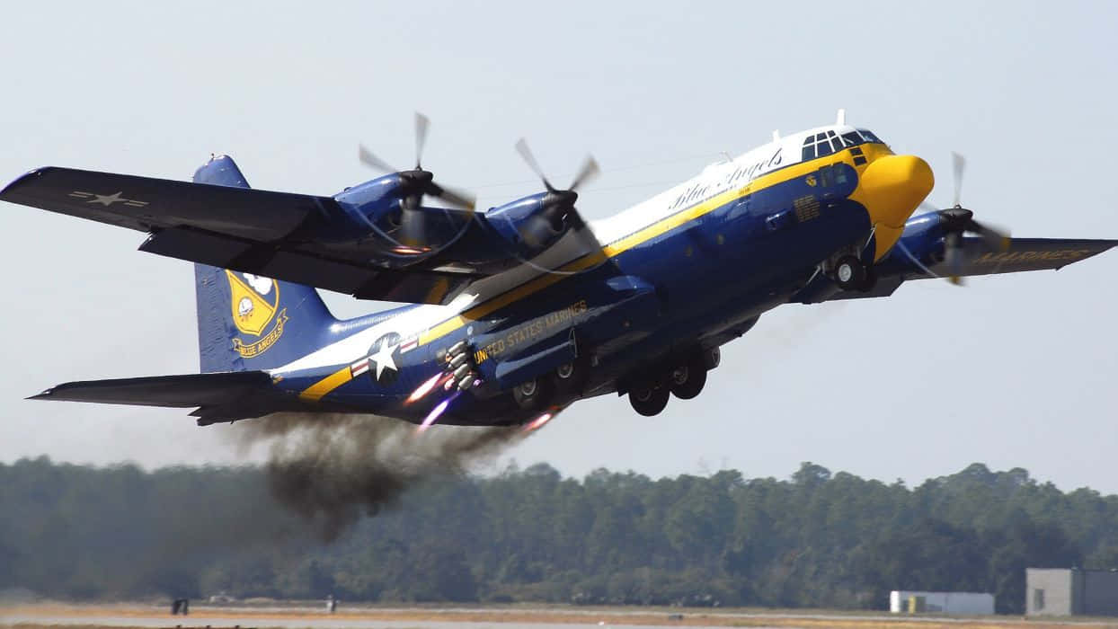 藍天使洛克希德C-130大力神運輸機 壁紙 — 一架藍天使C-130大力神飛機以藍、黃、白色塗裝，在跑道上低空飛過，後燃器轟鳴。
