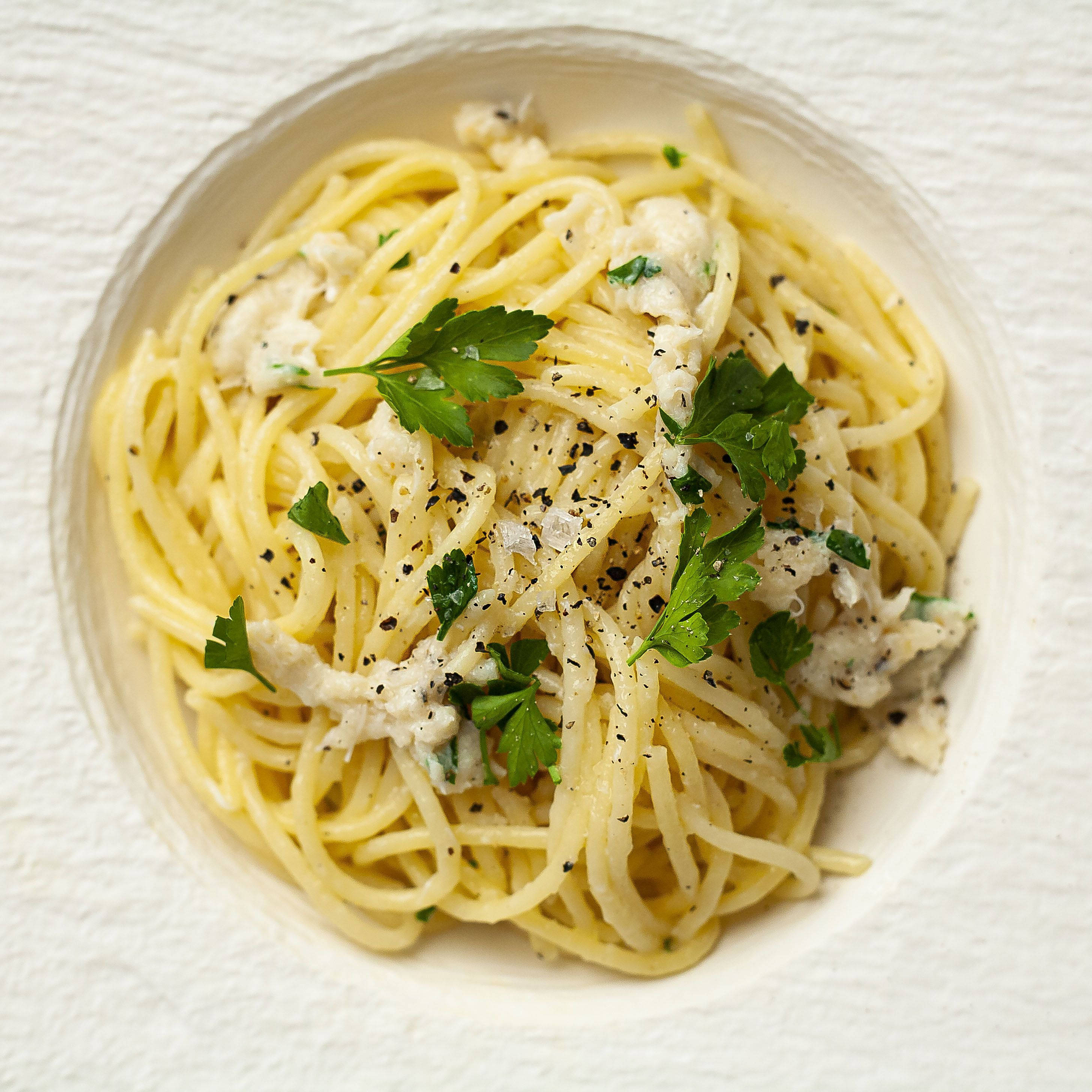 搭配羅勒葉的 Cacio E Pepe 壁紙 — 一個白色碗中的忌廉雞肉意粉，飾以新鮮歐芹和黑胡椒。