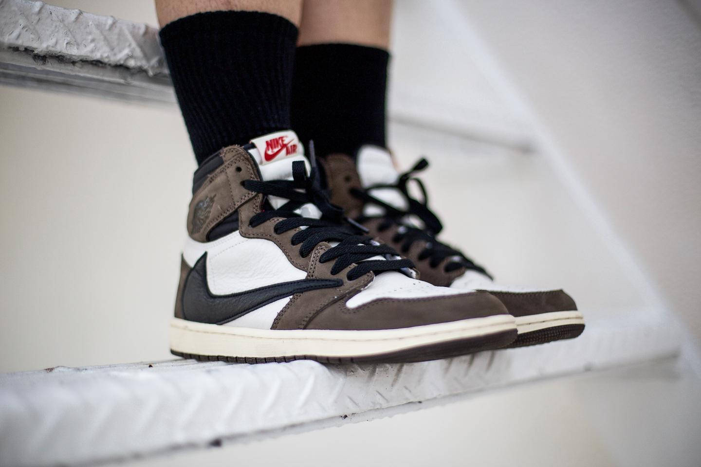 棕色、黑色和白色的 Nike Air Jordan 運動鞋放在白色樓梯上，搭配黑色襪子。