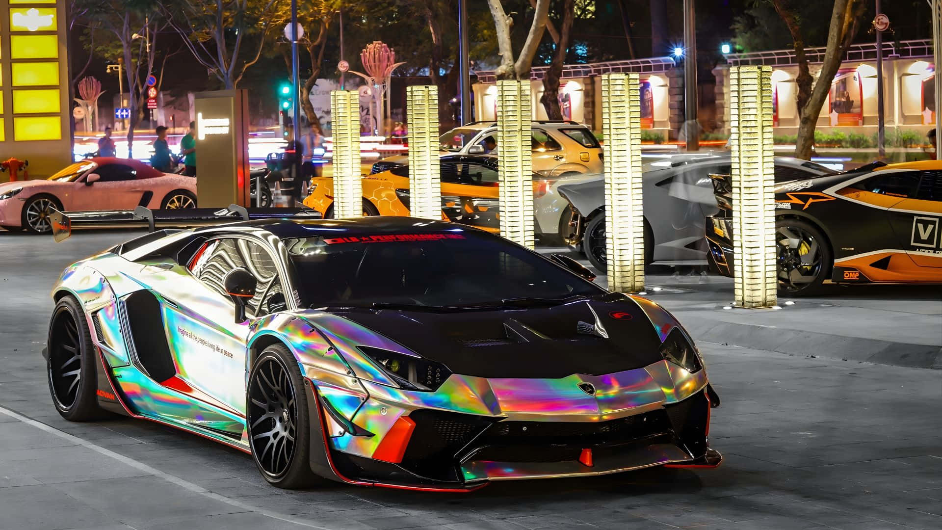  壁紙 — 一輛耀眼的彩虹色林寶堅尼跑車在夜間停泊在繁華的城市街道上，在城市的燈光下閃閃發光。