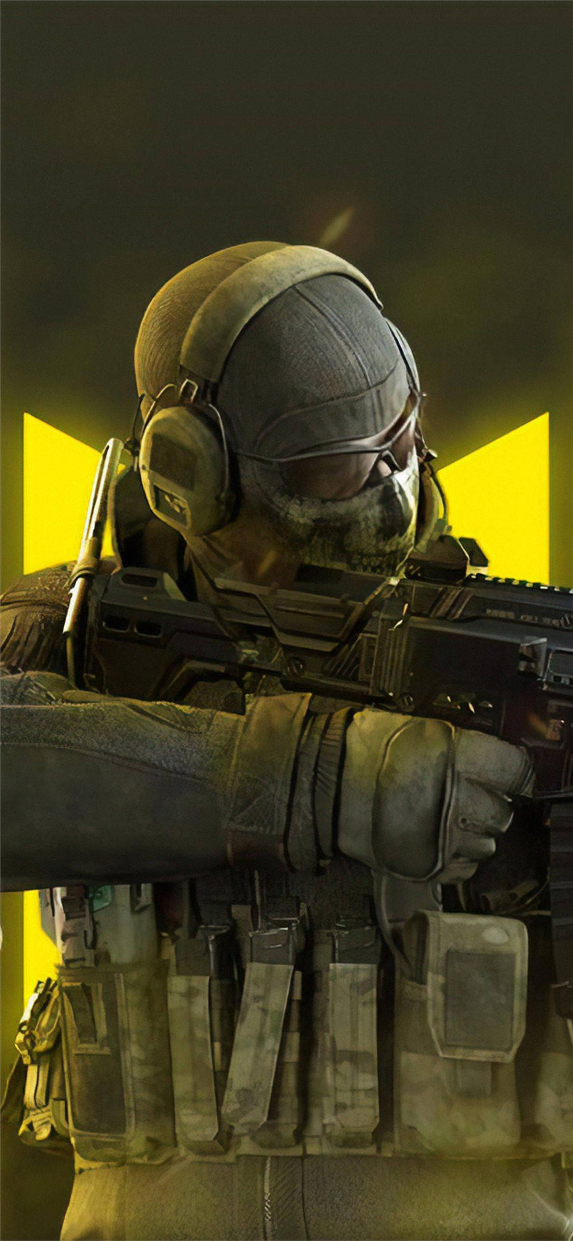 Call Of Duty Mobile Logo Ghost Close-up 壁紙 — 一名身穿戰術裝備的士兵在發光的黃色背景和黑暗陰影中瞄準步槍。