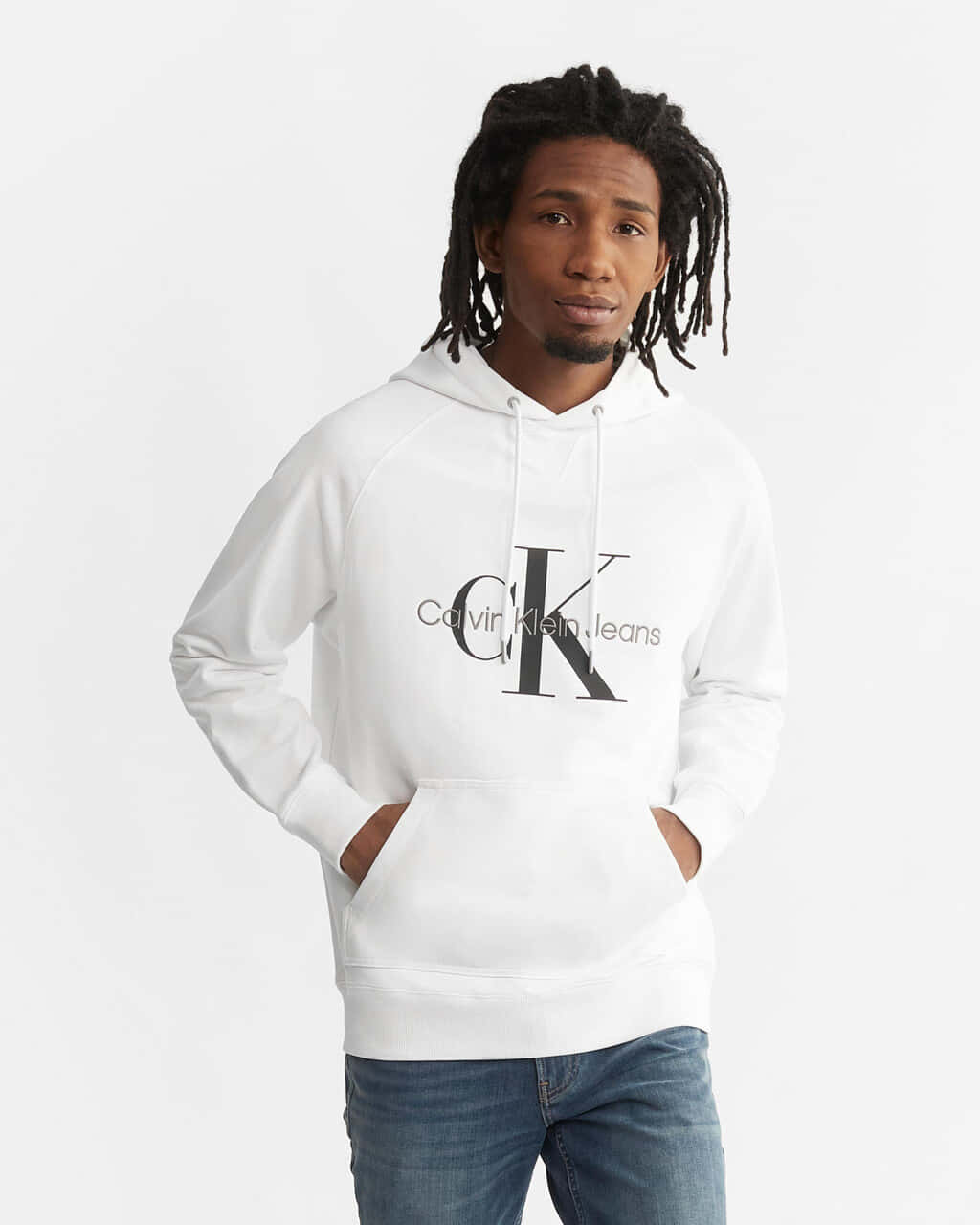 性感時尚的Calvin Klein穿搭 壁紙 — 一位留著辮子的年輕男子，身穿白色Calvin Klein連帽衫和牛仔褲，背景為純白色。