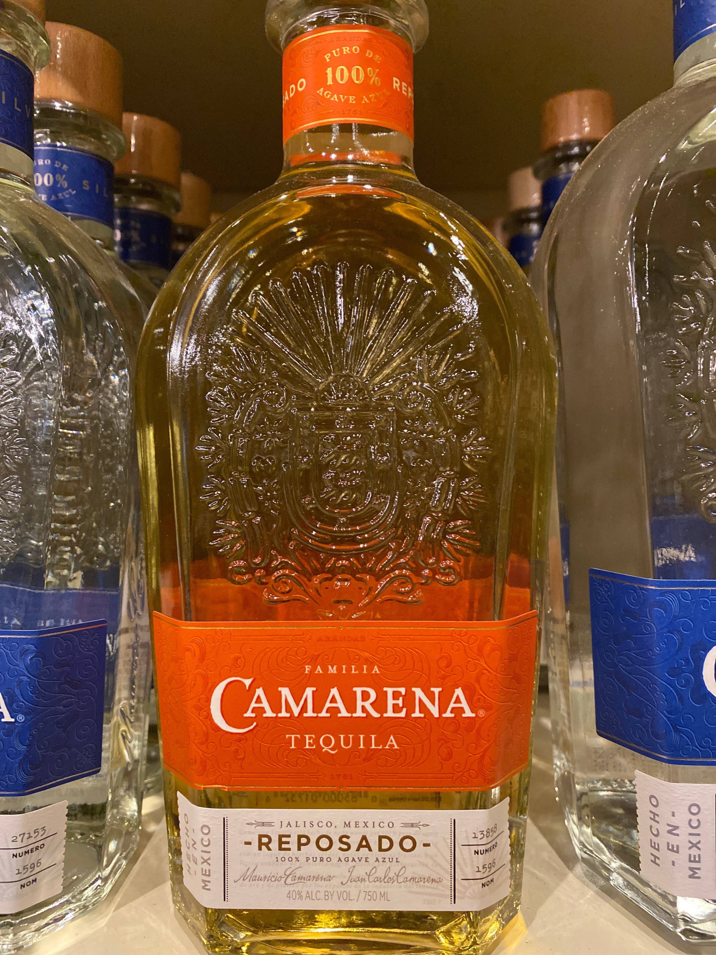 Camarena Reposado 閉合瓶蓋徽章 壁紙 — Camarena Reposado 龍舌蘭酒瓶的特寫，瓶內琥珀色液體，玻璃上帶有精緻浮雕設計。