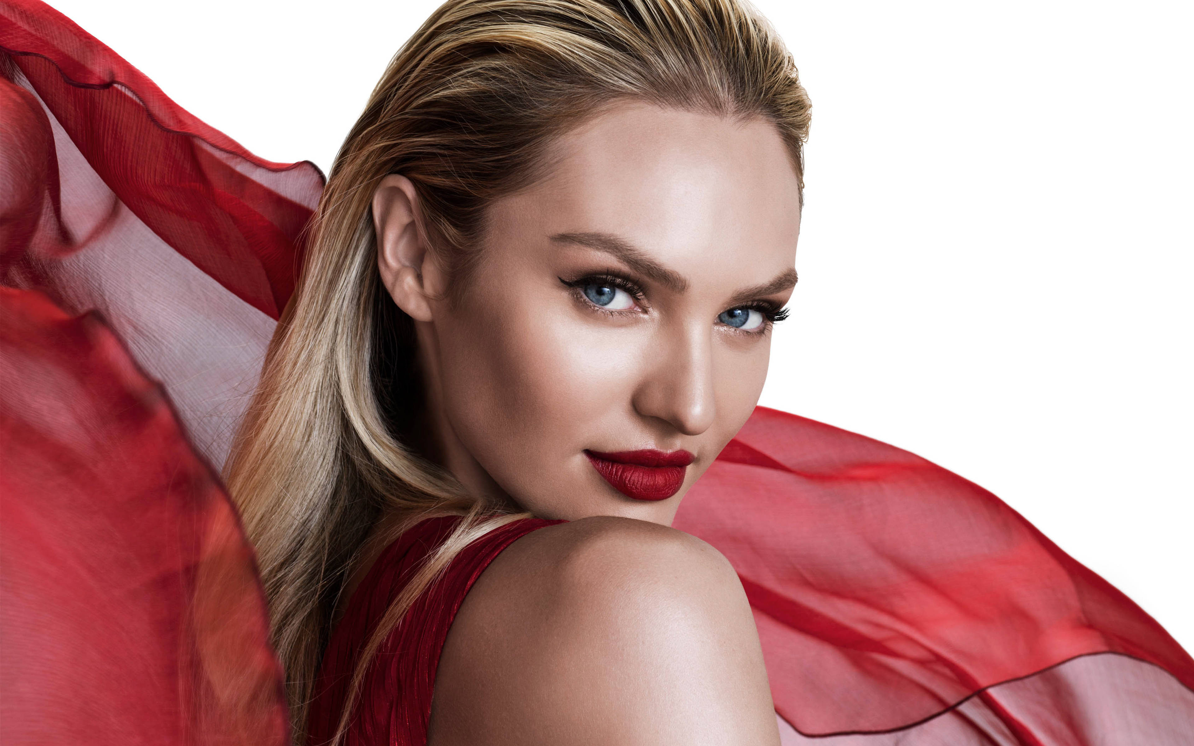 Candice Swanepoel 紅色薄紗圍巾攝影 壁紙 — 一位引人注目的金髮女郎，擁有鮮豔的紅唇和飄逸的紅色布料，在純白背景前自信地凝視。