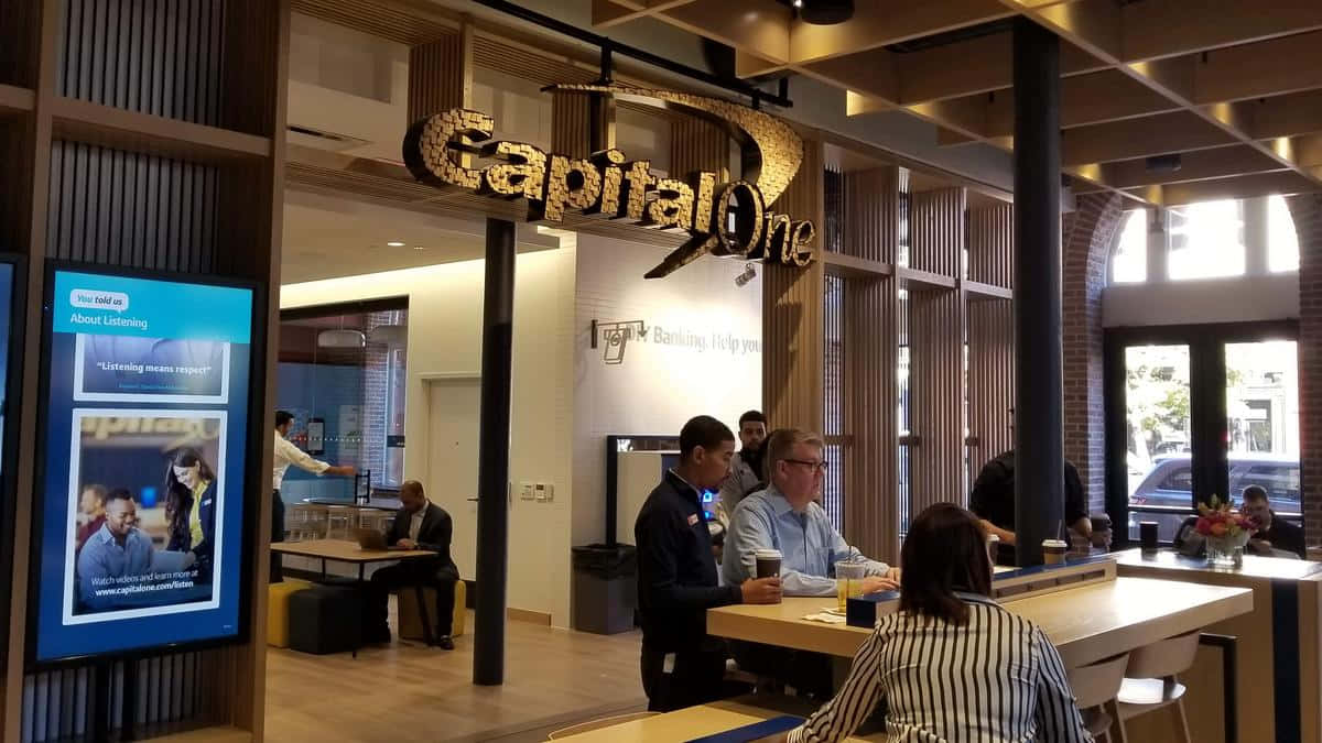 現代Capital One銀行內的顧客和員工，配有木桌和數碼顯示屏。